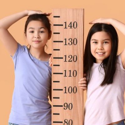 two children stand either side of a height chart